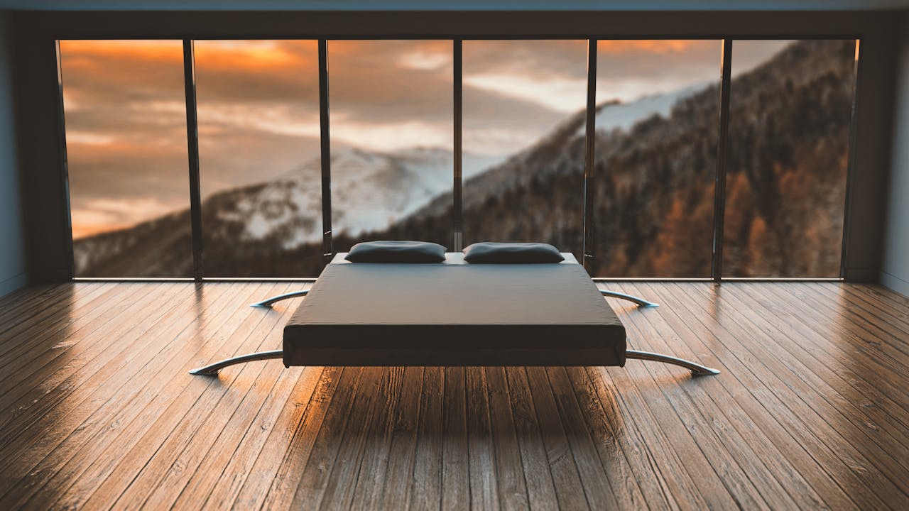 Home Minimalist bedroom with large windows offering a breathtaking mountain view during sunset.